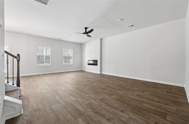 a view of an empty room with a window and wooden floor