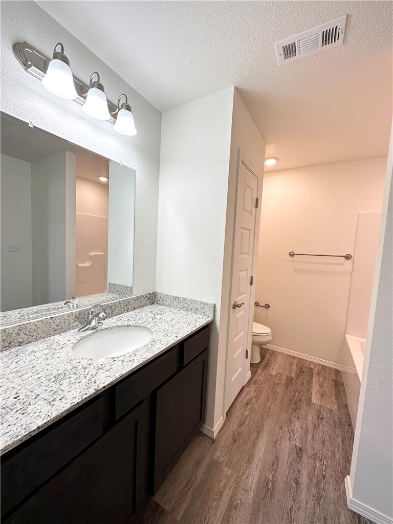 959 South Rupple Road, Unit 4 Fayetteville, AR 72704 - Photo 19 of 25 This bathroom features a vanity with a white granite countertop and a single basin, dark wood cabinetry, and a large mirror
