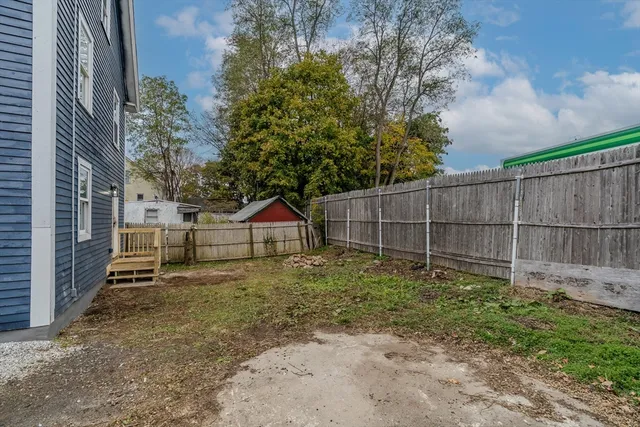 a view of a brick house with wooden deck and furniture