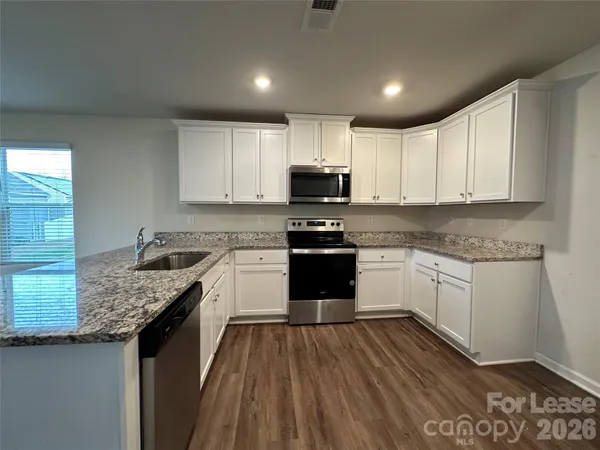 a kitchen with granite countertop a sink a counter top space stainless steel appliances and cabinets
