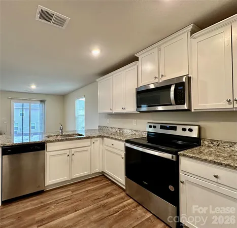 a kitchen with stainless steel appliances granite countertop a stove sink microwave and cabinets