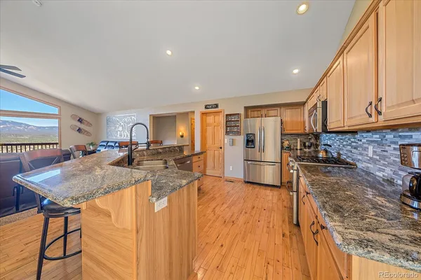 a kitchen with stainless steel appliances granite countertop a sink refrigerator and cabinets
