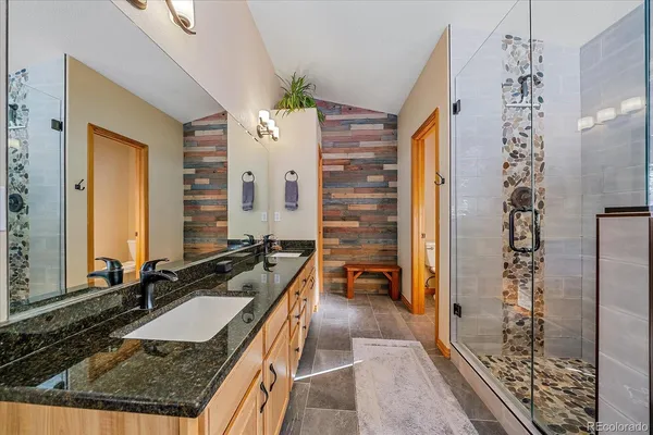 a bathroom with a granite countertop sink a mirror and shower