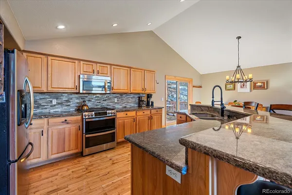 a kitchen with stainless steel appliances granite countertop a sink a stove and a wooden floors