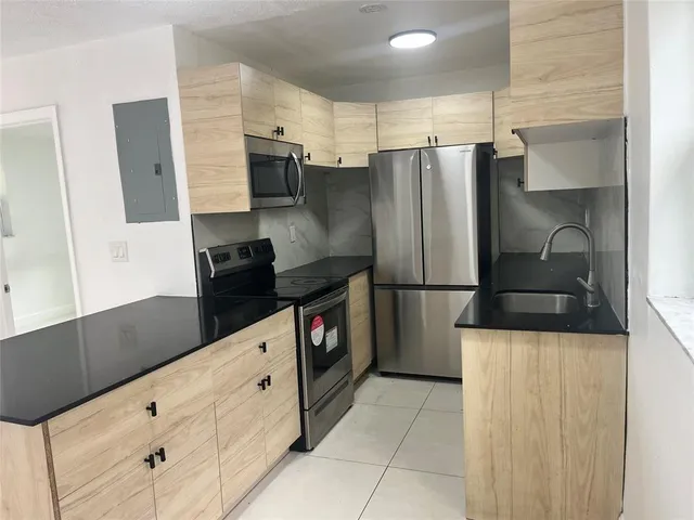 a kitchen with granite countertop a refrigerator and a stove top oven