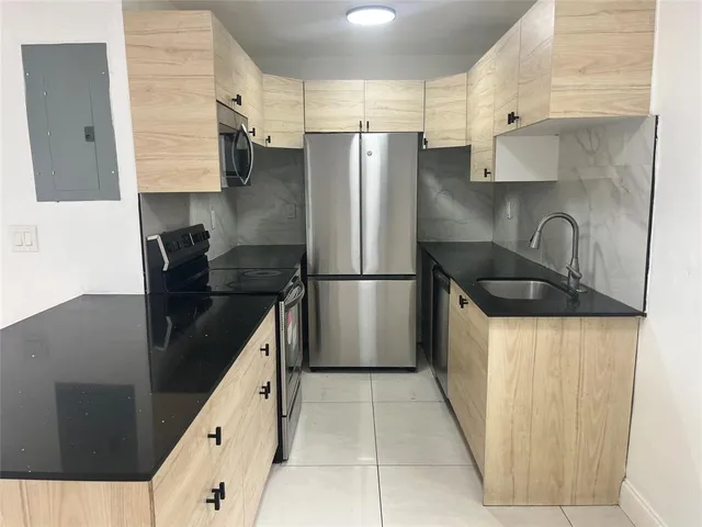 a kitchen with granite countertop a refrigerator and a sink