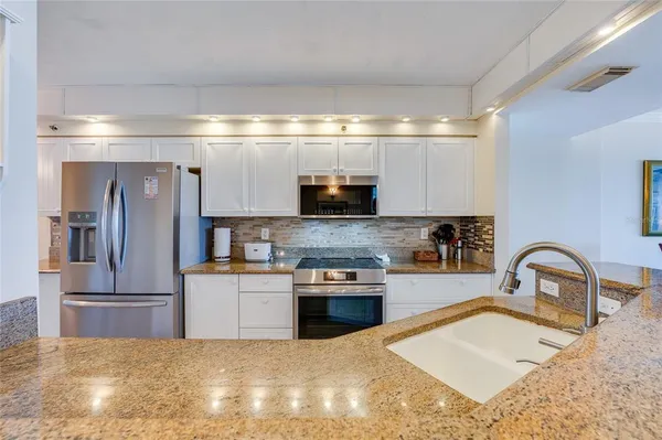 a kitchen with stainless steel appliances granite countertop a sink and a refrigerator