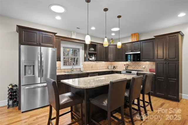 a kitchen with stainless steel appliances granite countertop a table chairs refrigerator and microwave