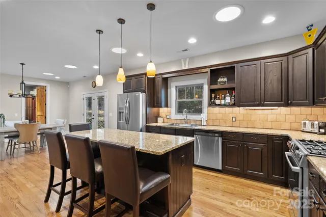 a kitchen with stainless steel appliances kitchen island granite countertop a table chairs and a sink