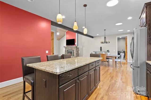 a kitchen with a table chairs refrigerator and wooden floor