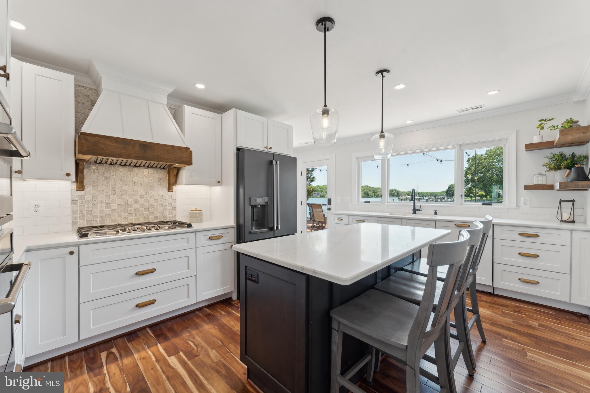 1045 Back Bay Beach Road West River, MD 20778 - Photo 18 of 33 a kitchen with stainless steel appliances kitchen island granite countertop a table chairs stove and white cabinets