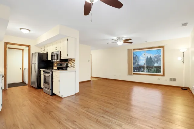 a view of kitchen and empty room with wooden floor