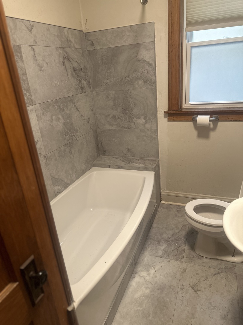 6837 South Maplewood Avenue, Unit 1R Chicago, IL 60629 - Photo 15 of 16 a bath tub sitting next to a white toilet