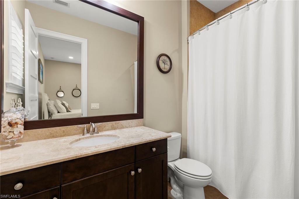 4922 Andros Drive Naples, FL 34113 - Photo 31 of 44 a bathroom with a double vanity sink toilet and a mirror