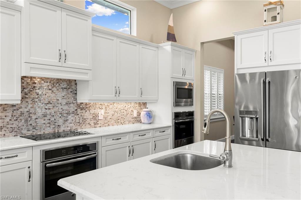 4922 Andros Drive Naples, FL 34113 - Photo 6 of 44 a kitchen with stainless steel appliances granite countertop a sink stove and refrigerator
