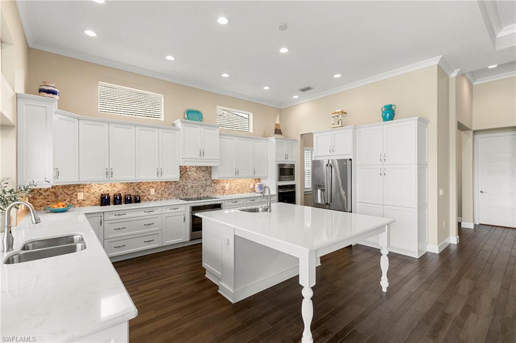 4922 Andros Drive Naples, FL 34113 - Photo 8 of 44 a large kitchen with a large counter top a sink stainless steel appliances and cabinets