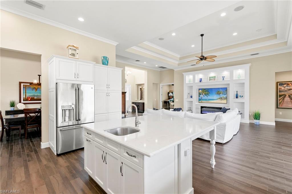 4922 Andros Drive Naples, FL 34113 - Photo 9 of 44 a kitchen with stainless steel appliances a refrigerator a sink dishwasher and a stove with wooden floor