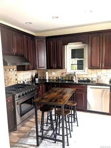 a kitchen with granite countertop wooden cabinets and a stove