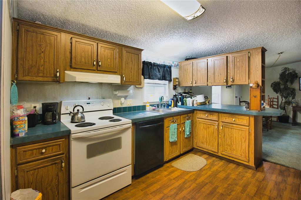 2498 Saturn Road Brooksville, FL 34604 - Photo 8 of 26 a kitchen with stainless steel appliances granite countertop a stove a sink dishwasher and a refrigerator with wooden cabinets