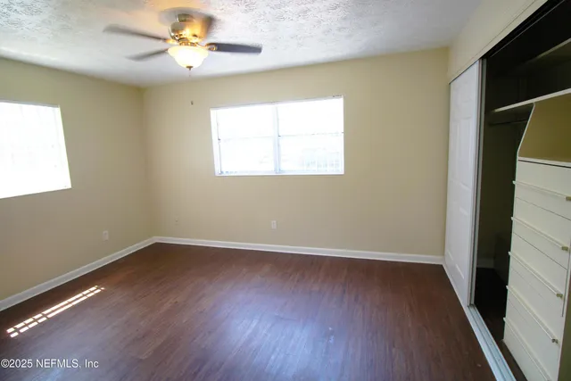 an empty room with wooden floor and windows