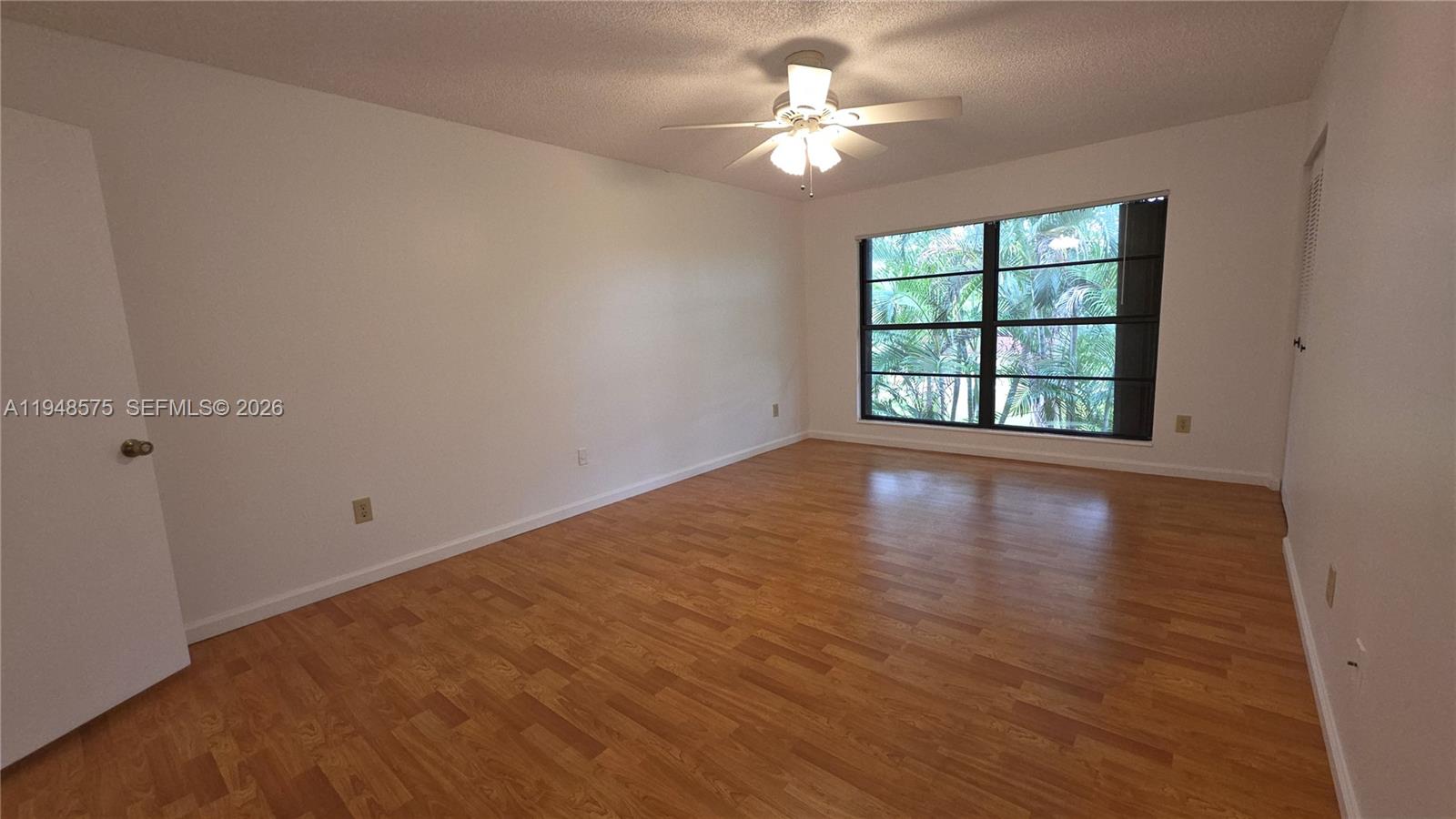 7124 Southwest 114th Place, Unit A Miami, FL 33173 - Photo 12 of 19 an empty room with wooden floor and windows