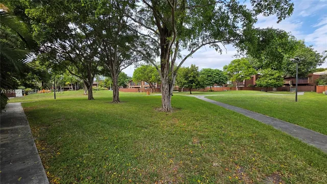 a view of grassy field with benches and trees all around