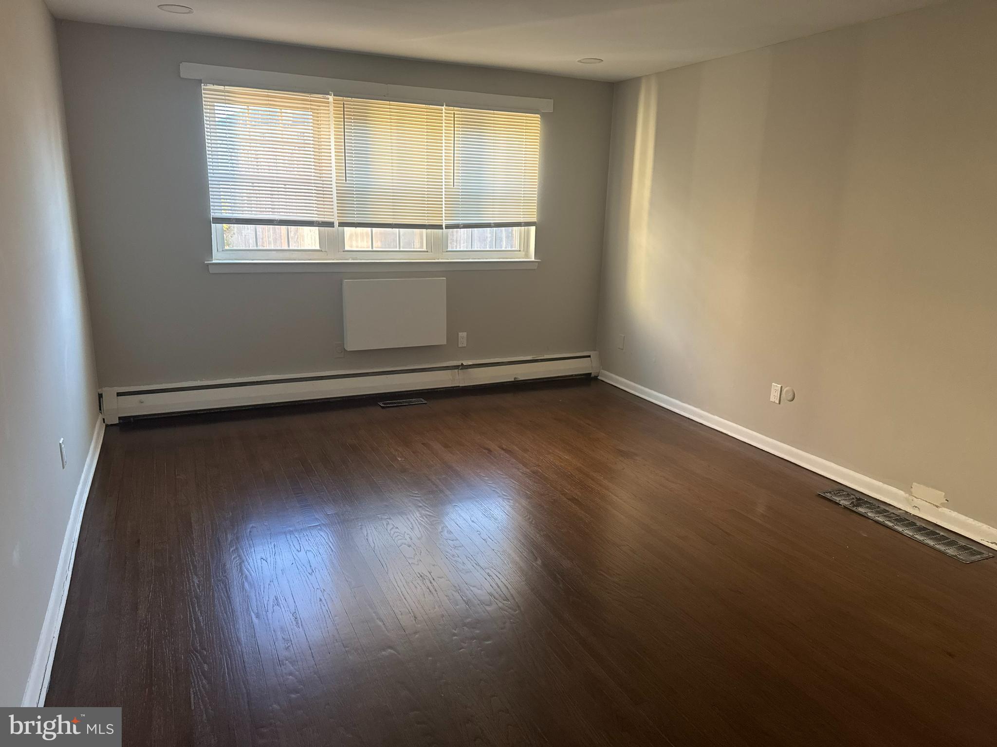 210 Trinity Avenue, Unit A1 Ambler, PA 19002 - Photo 4 of 8 an empty room with wooden floor and windows