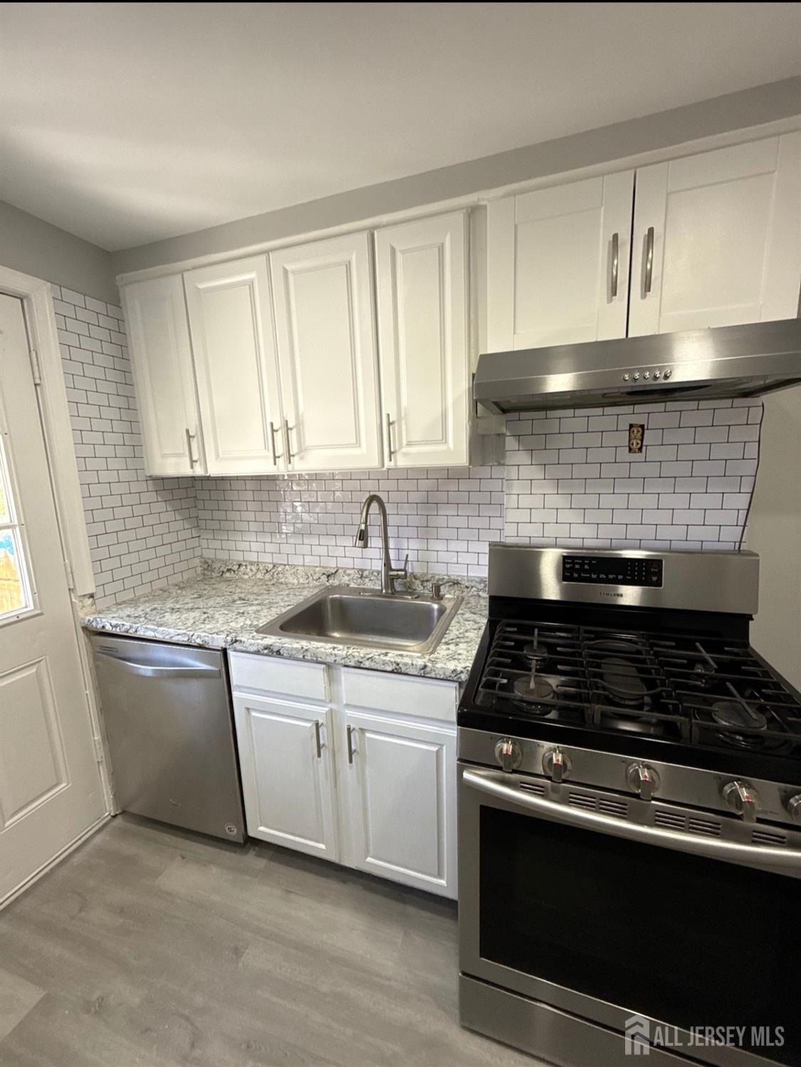 42 MacArthur Drive Edison, NJ 08837 - Photo 4 of 10 a kitchen with stainless steel appliances granite countertop white cabinets and a stove top oven