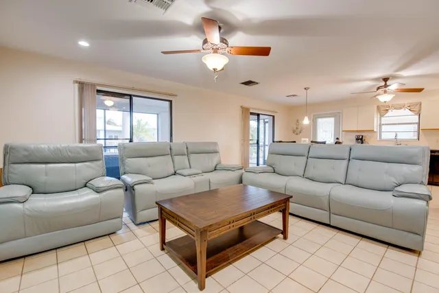 a living room with furniture a chandelier fan and a window