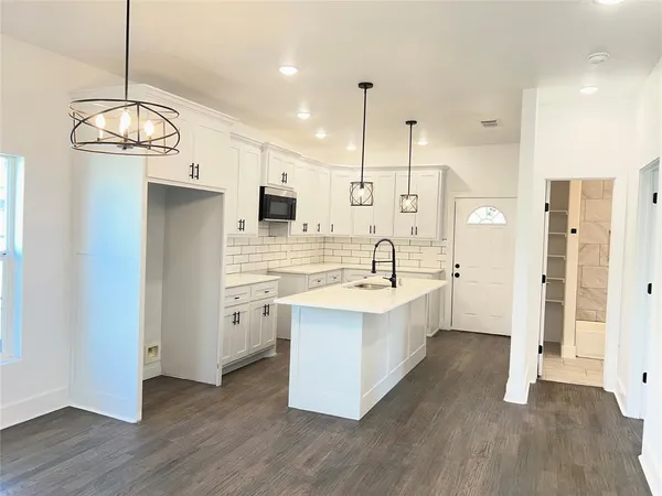 a large kitchen with a center island wooden floor and stainless steel appliances