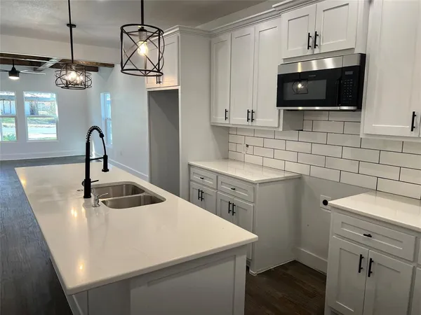 a kitchen with a sink a microwave and cabinets