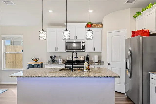 a kitchen with kitchen island granite countertop a sink a counter space and appliances