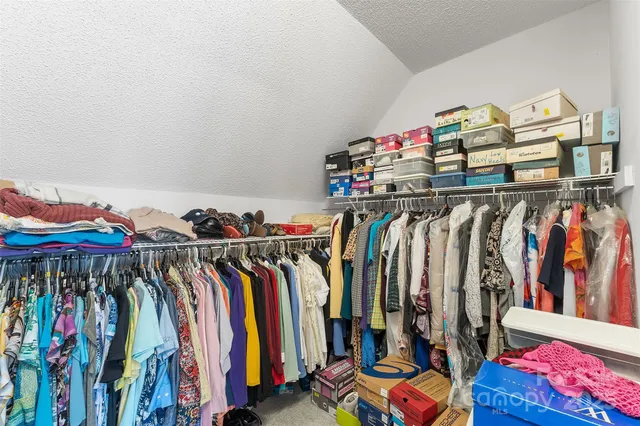a view of walk in closet with clothes and shoes