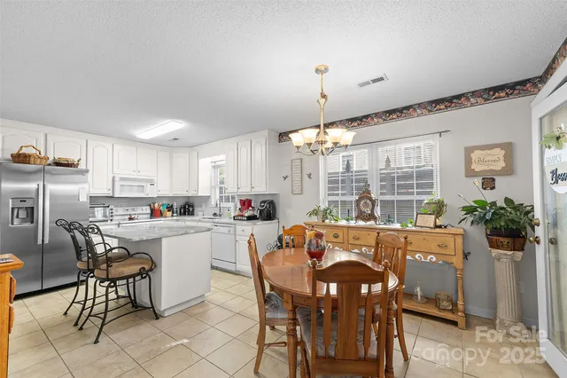 a kitchen with stainless steel appliances a dining table chairs and granite counter tops