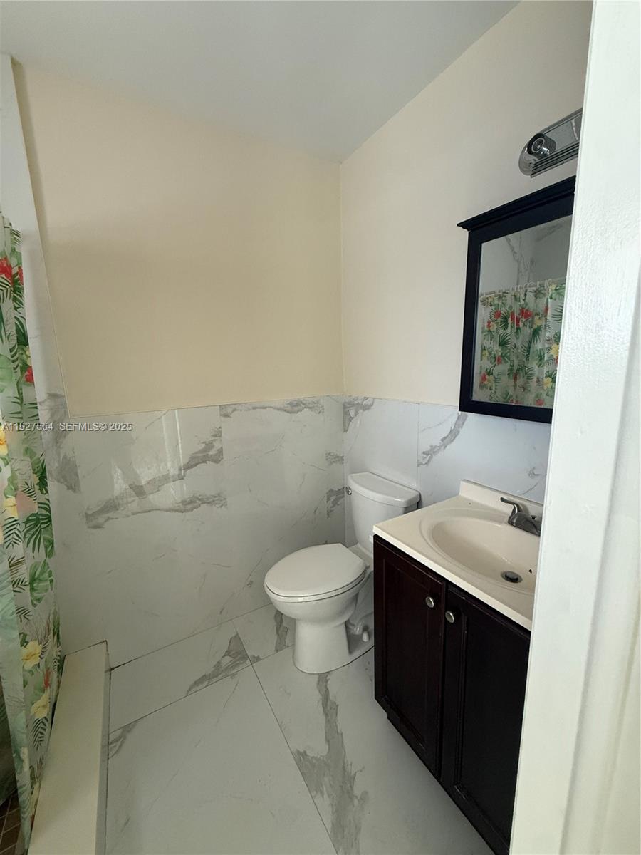1211 Northeast 23rd Avenue, Unit 5 Pompano Beach, FL 33062 - Photo 10 of 10 a bathroom with a toilet a sink and mirror