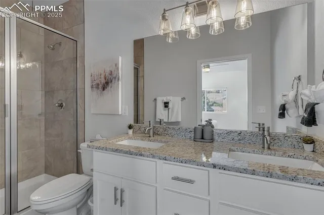 a bathroom with a granite countertop sink a toilet and shower