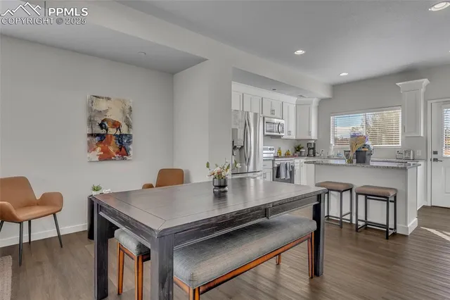 a kitchen with a dining table chairs and refrigerator