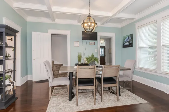 a dining room with wooden floor a chandelier a wooden table and chairs