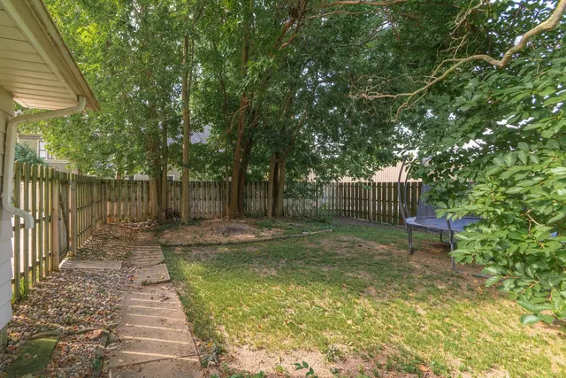 a view of a backyard with wooden fence and a bench