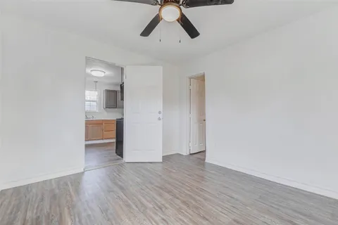 a view of empty room with wooden floor and ceiling fan