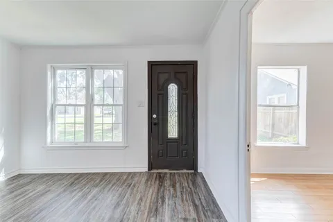 an empty room with wooden floor closet and windows