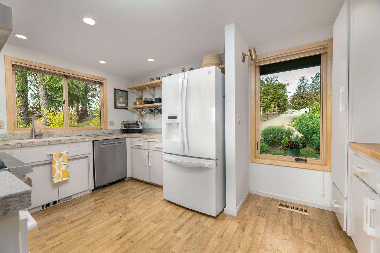 16105 John Way Grass Valley, CA 95949 - Photo 21 of 71 a kitchen with a refrigerator a sink and white cabinets with wooden floor