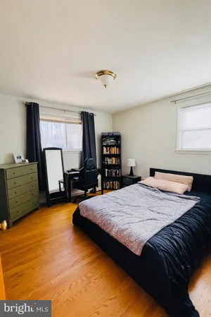 a bedroom with a bed dresser and a large window