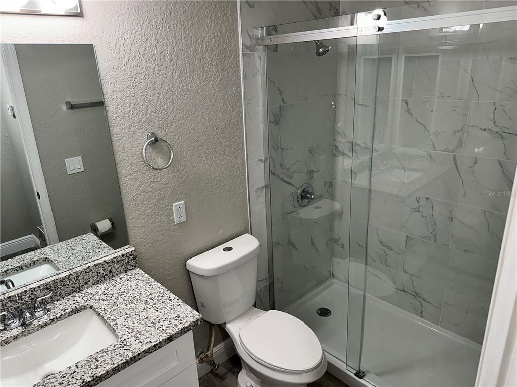 1025 South Hiawassee Road, Unit 2214 Orlando, FL 32835 - Photo 12 of 26 a bathroom with a granite countertop toilet a sink a shower and a mirror