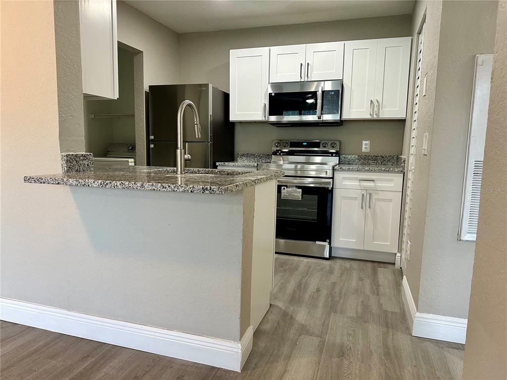 1025 South Hiawassee Road, Unit 2214 Orlando, FL 32835 - Photo 2 of 26 a kitchen with stainless steel appliances granite countertop a stove top oven a sink and a microwave