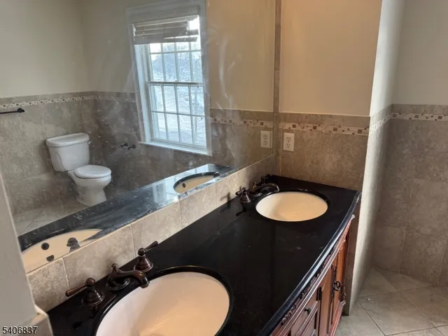 a bathroom with a granite countertop toilet sink and mirror