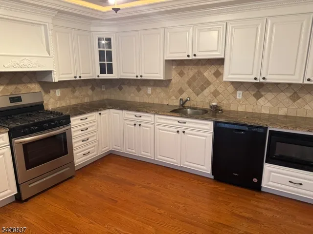 a kitchen with stainless steel appliances granite countertop a stove a sink and white cabinets