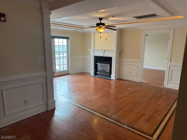 an empty room with wooden floor fireplace and windows