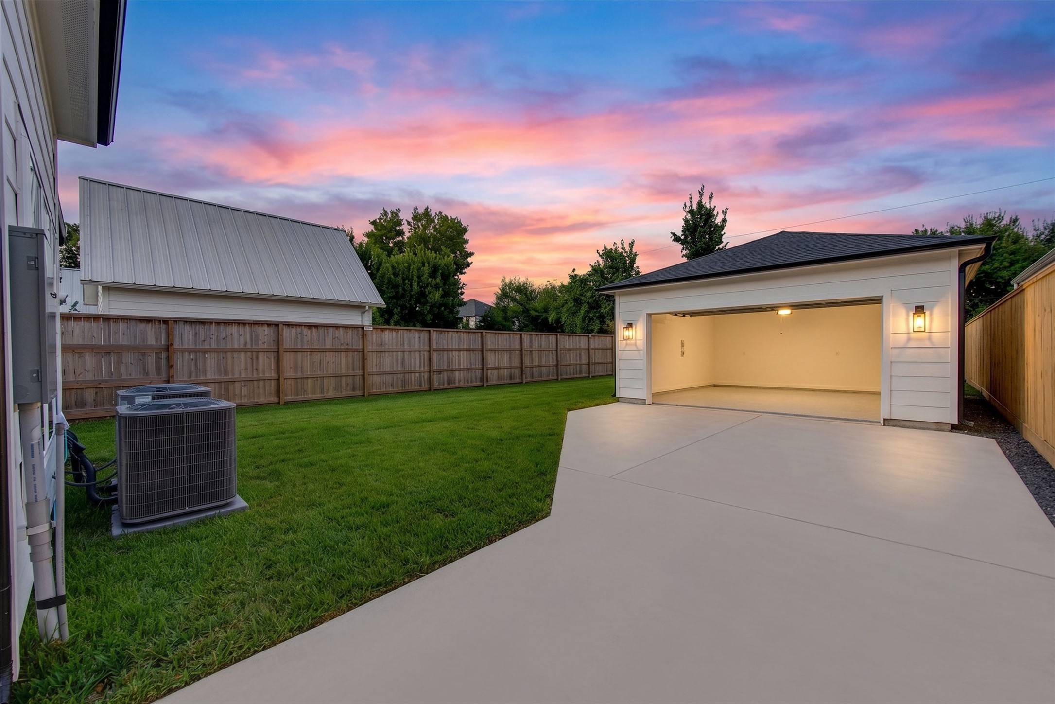 2309 Hollister Road Houston, TX 77080 - Photo 36 of 47 A private driveway leads to the detached garage, offering exceptional parking, storage, and everyday convenience. Framed by a fenced lawn and captured beneath a dramatic sunset, this generous outdoor area highlights the property’s sense of space and versatility—ideal for additional recreation, entertaining, or future customization.
