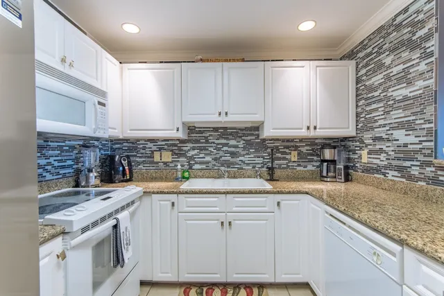 a bedroom with a bed a chandelier and a dresser next to a window